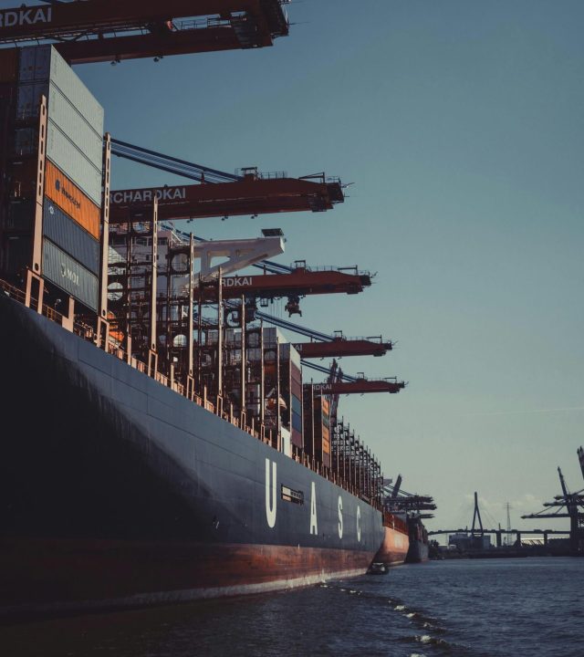 pexels-photo-1095814-1095814 A large cargo ship docked at Hamburg Harbor, cranes loading containers under a clear sky.